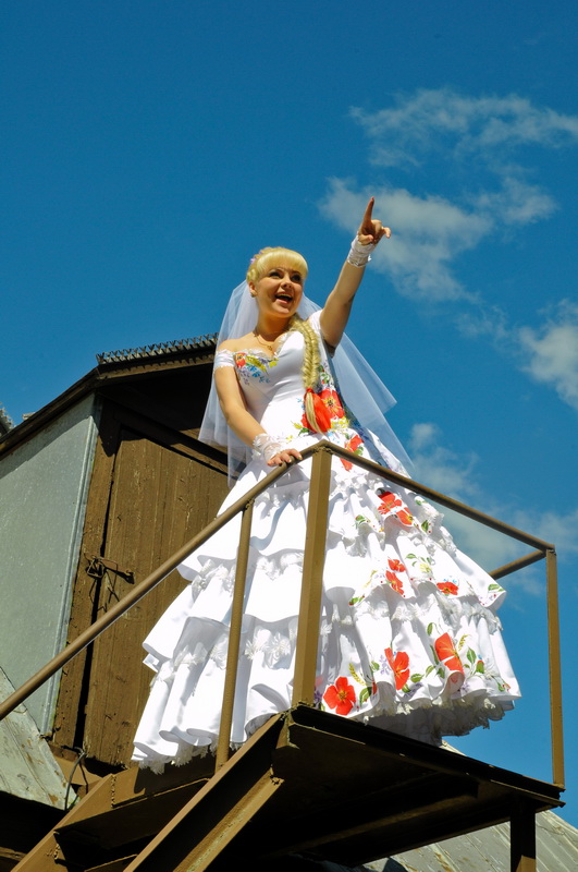 Нетерпеливая невеста, выглядывающая своего жениха с крыши дома. Жанровая свадебная фотография. Автор Сергей Рыжков